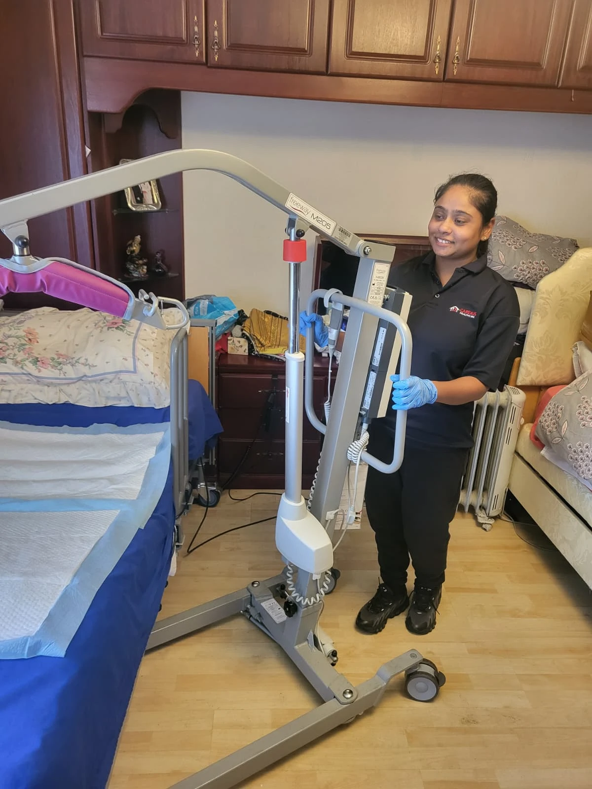 Care4Us carer operating a patient hoist lift next to a hospital bed during a home care visit